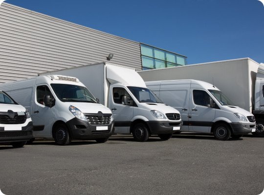 Flotte de véhicules utilitaires KARBOLOG stationnés devant une plateforme logistique